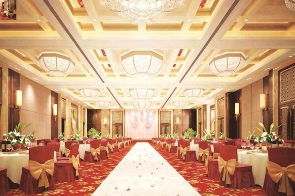 Un salón de banquetes con una larga mesa, sillas y piso alfombrado.