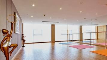 A spacious room with wooden flooring, a glass partition, and exercise mats.