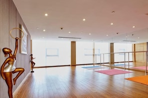 A spacious room with wooden flooring, a glass partition, and exercise mats. - Huaxi Hotel (Laixi)