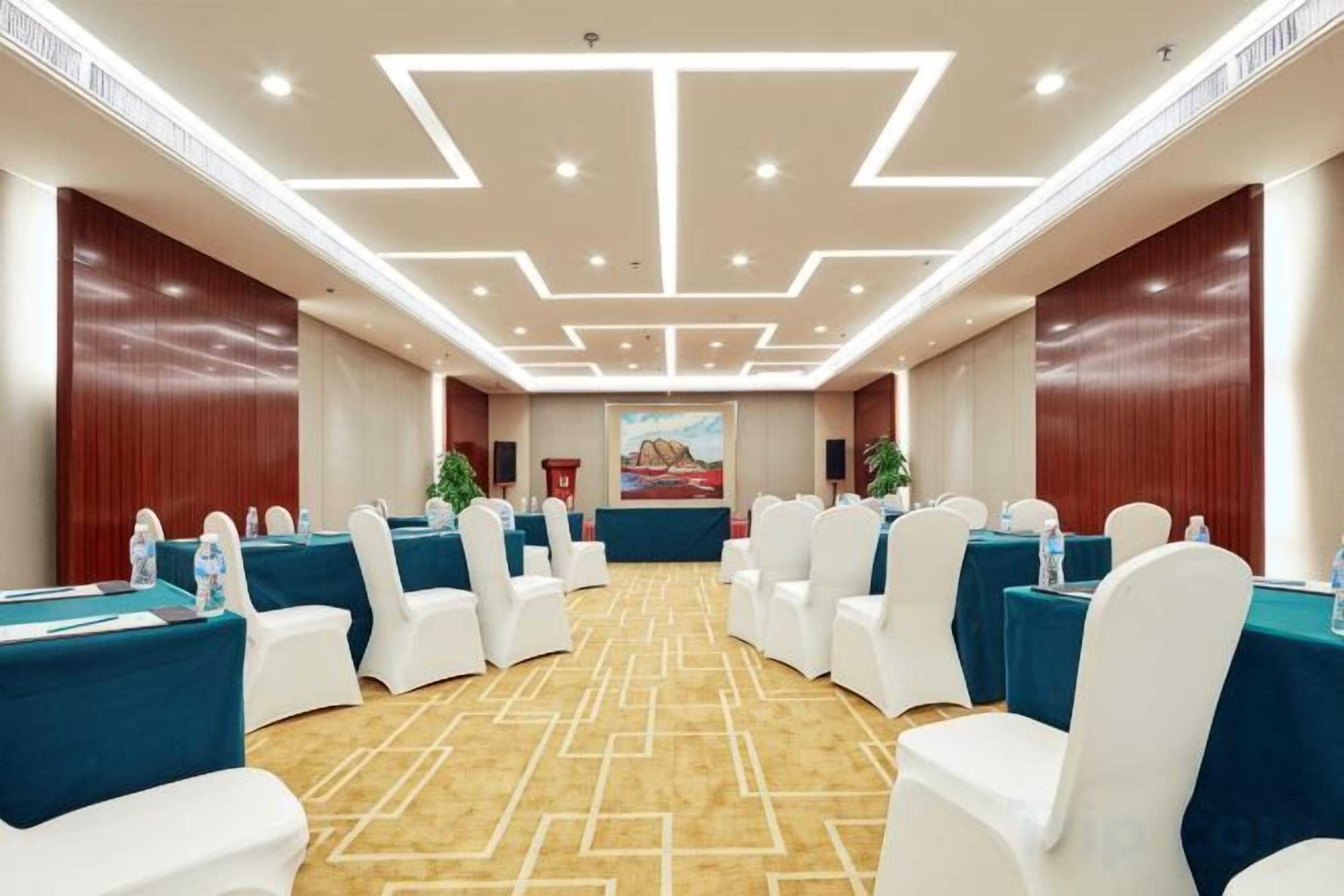 A conference room with round tables, white chairs, and a carpeted floor.