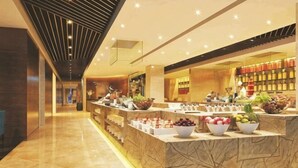 Un vestíbulo de hotel con un mostrador de recepción de mármol, una exhibición de frutas y una zona de estar.