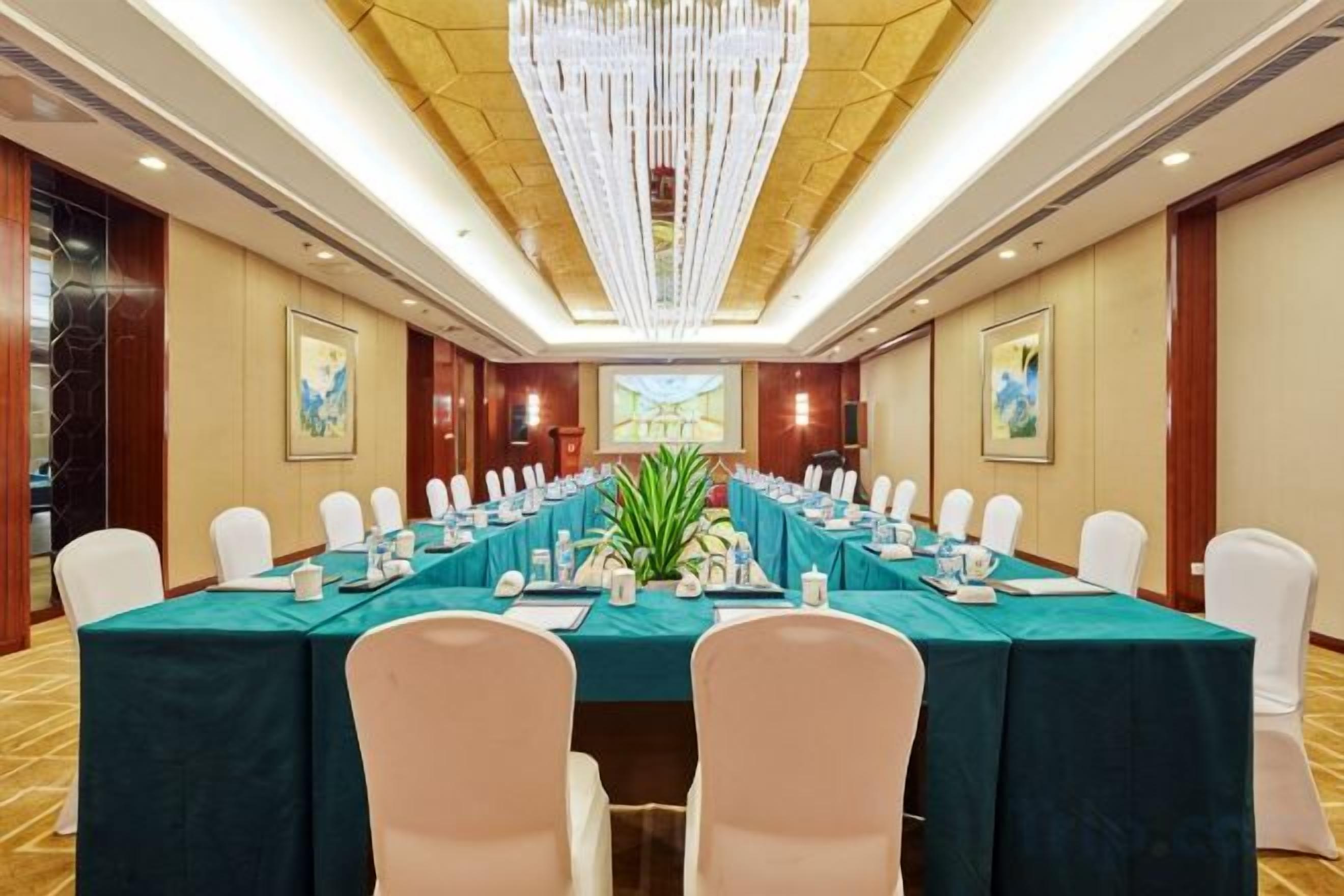 A conference room with a long table, white chairs, and a chandelier.