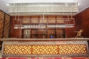 A bar area with a counter, shelves with glasses, and a decorative sculpture. - Huaxi Hotel (Laixi)