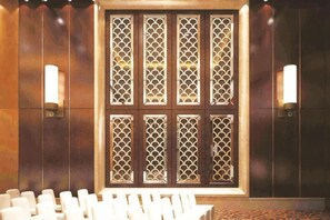 A conference room with a patterned partition, white chairs, and wall-mounted lights. - Huaxi Hotel (Laixi)