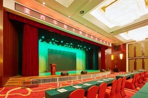 A conference room with a stage, a long table with chairs, and a red carpet. - Huaxi Hotel (Laixi)