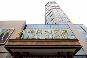 A hotel sign with large golden letters and a modern building facade. - Huaxi Hotel (Laixi)