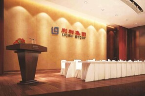 A conference room with a podium, tables, and chairs, and a wall with a company logo. - Huaxi Hotel (Laixi)