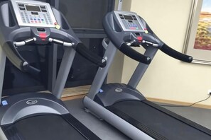 Two treadmills with control panels, positioned next to a window with a view of a desert landscape. - Huaxi Hotel (Laixi)