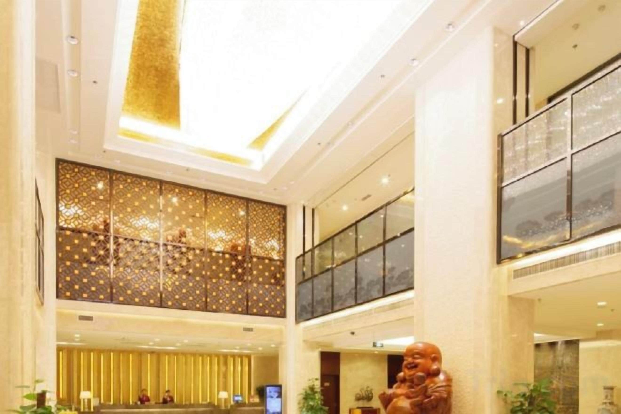 A multi-level hotel lobby with a reception desk, seating area, and a large decorative sculpture.
