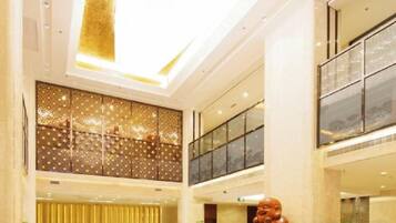 A multi-level hotel lobby with a reception desk, seating area, and a large decorative sculpture.