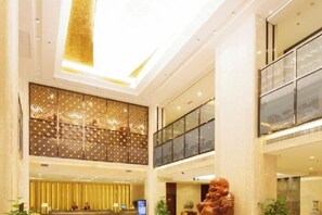 A multi-level hotel lobby with a reception desk, seating area, and a large decorative sculpture. - Huaxi Hotel (Laixi)