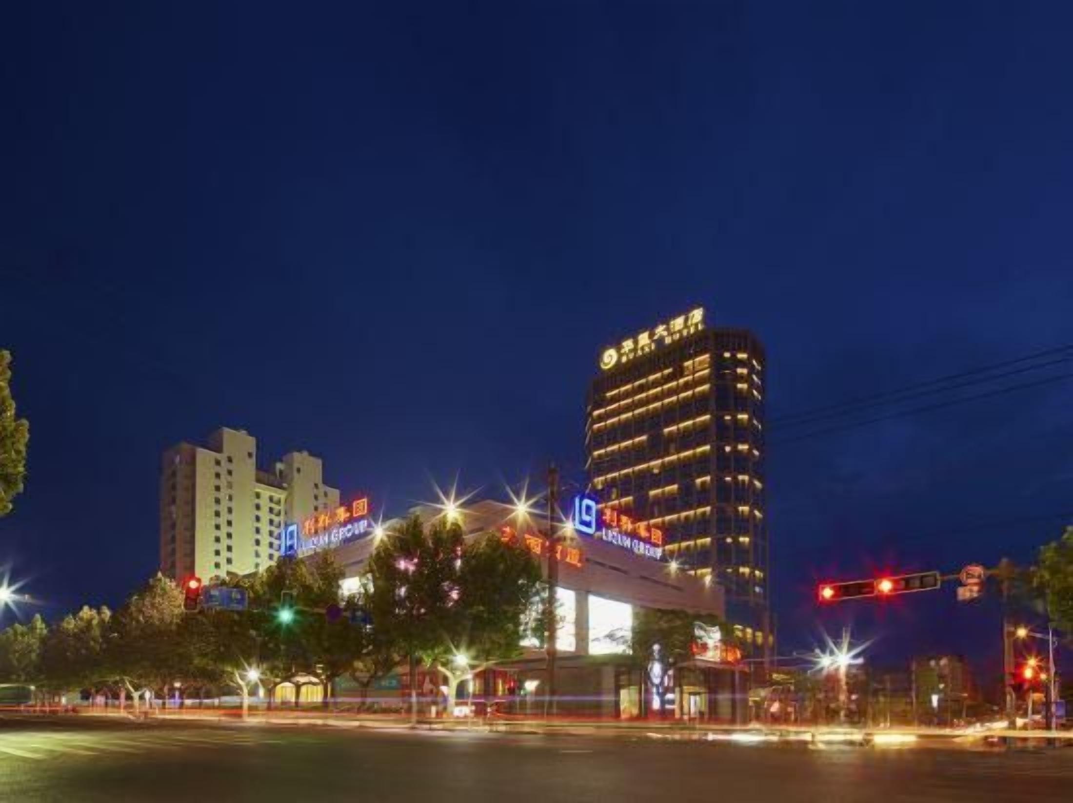 A multi-story hotel with illuminated signage, a prominent entrance, and a view of the surrounding urban area at night.
