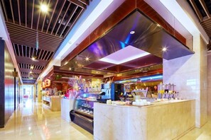 A modern hotel lobby with a central reception desk, a glass display case, and a high ceiling with lighting fixtures.