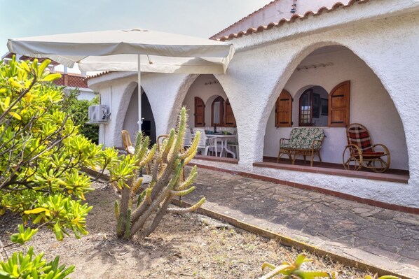A building with white stucco walls, arched doorways, and outdoor seating with wicker furniture.