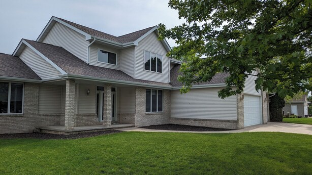 A two-story house with a garage, a covered porch, and a well-maintained lawn. -   LARGE HOME 30 mi TO LAMBEAU FIELD GREEN BAY AND ONLY 25 mi to EAA OSHKOSH (Appleton)