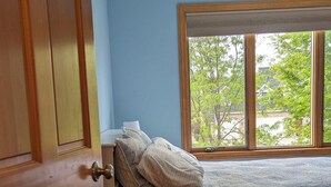 A bedroom with a bed, a window with a view of trees, and a wooden door. -   LARGE HOME 30 mi TO LAMBEAU FIELD GREEN BAY AND ONLY 25 mi to EAA OSHKOSH (Appleton)