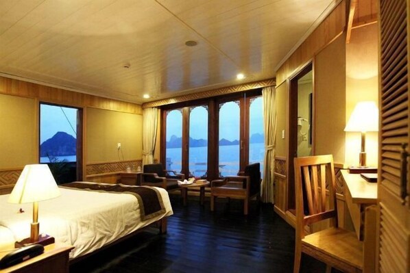 Une chambre d’hôtel avec un lit, deux chaises, une table et une vue sur la mer.