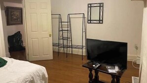 Ein Hotelzimmer mit einem Bett, einem Fernseher auf einem Holztisch, einer weißen Tür und einer schwarzen Metallregaleinrichtung.
