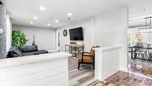 Una sala de estar moderna con un sofá, un televisor y un comedor con sillas y una mesa.
