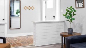 Una sala moderna con un banco de madera, un sofá, una mesita y una planta en maceta.
