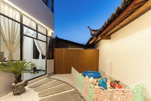 A traditional building with a wooden door, a small garden area with stepping stones, and colorful plastic chairs. - YUNZHINAN HOTEL (Lijiang)