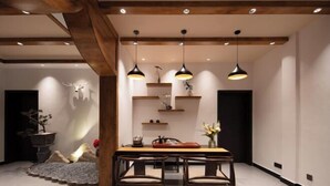 Uma área de refeições moderna com mesa e cadeiras de madeira, iluminação pendente e um detalhe decorativo na parede.