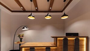 Uma receção com acabamento em madeira e design moderno, acompanhada por três luminárias pendentes e um candeeiro de chão.