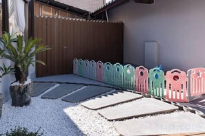 A garden with stepping stones, a potted plant, and a wooden fence. - YUNZHINAN HOTEL (Lijiang)