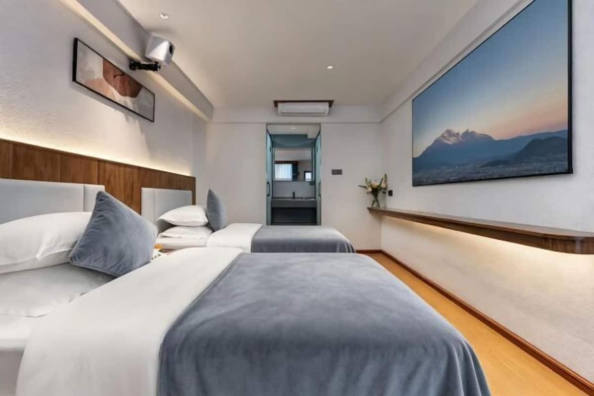 A hotel room with two beds, a large window, and a painting on the wall.