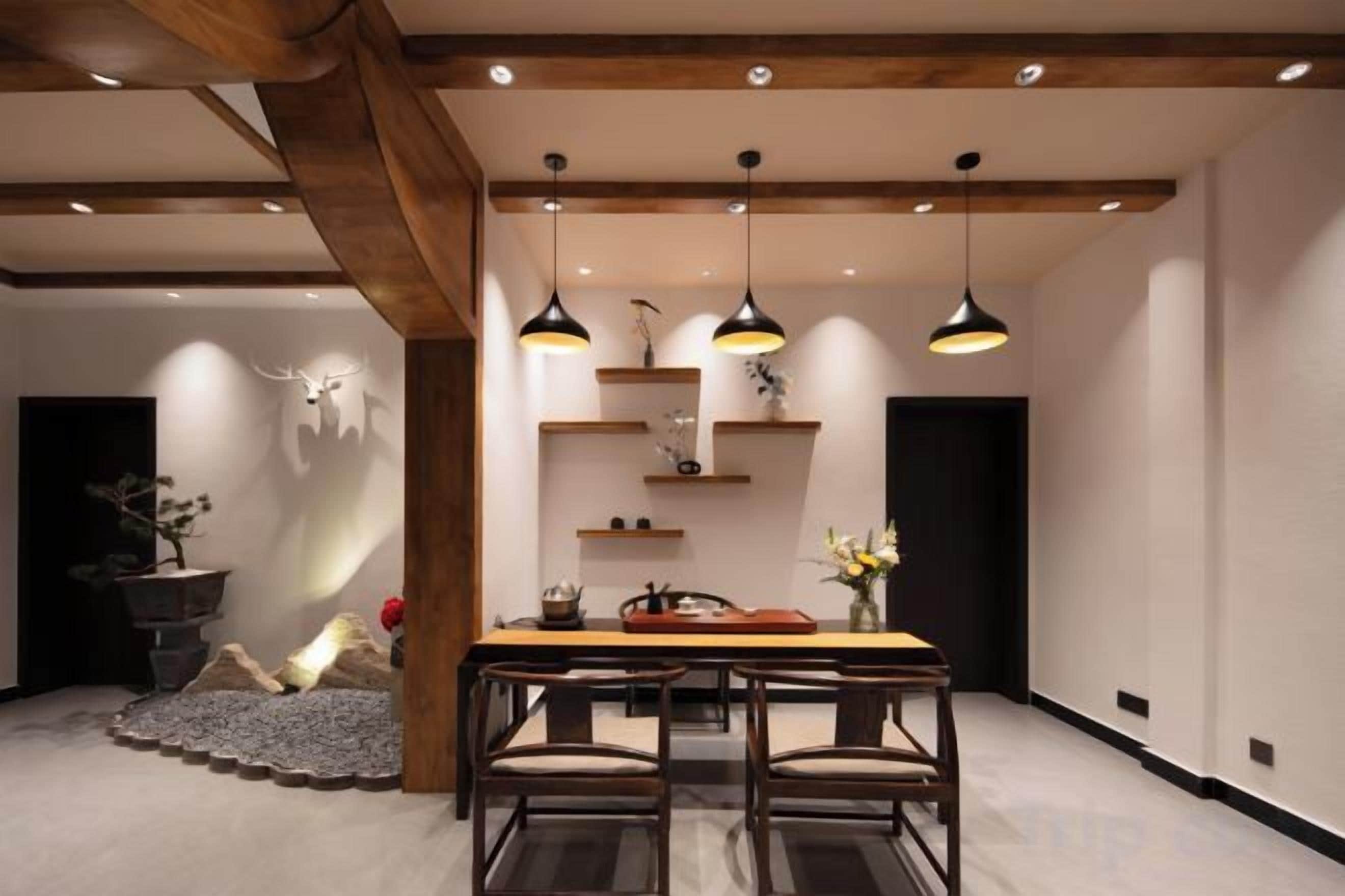 A modern dining area with a wooden table and chairs, pendant lighting, and a decorative wall with shelves.