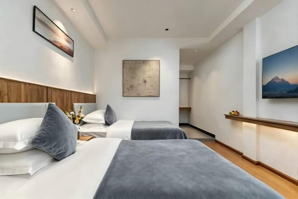 A hotel room with two beds, a wooden headboard, a large abstract painting, and a framed picture on the wall.