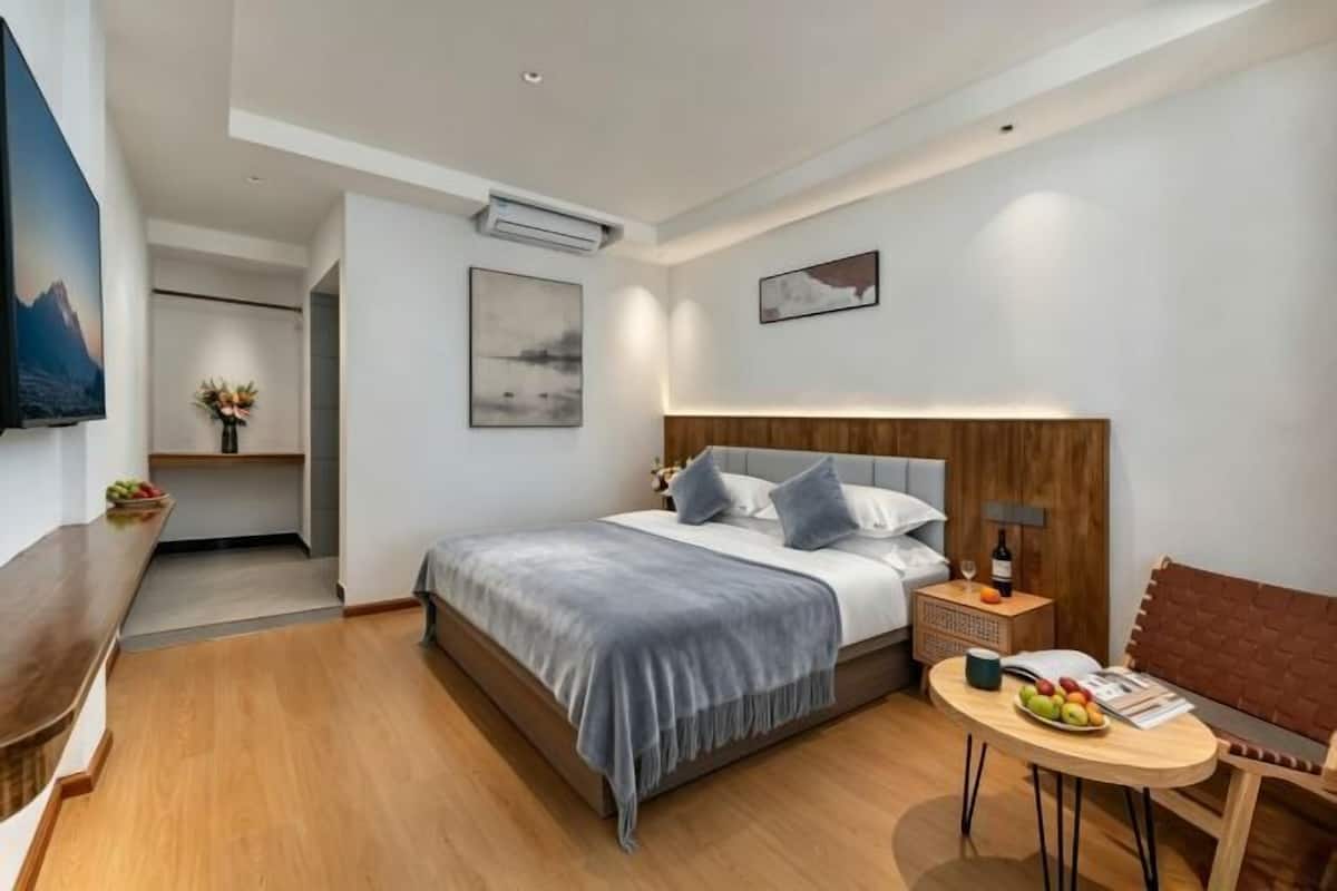 A modern hotel room with a bed, bedside table, and a small round table with fruit.