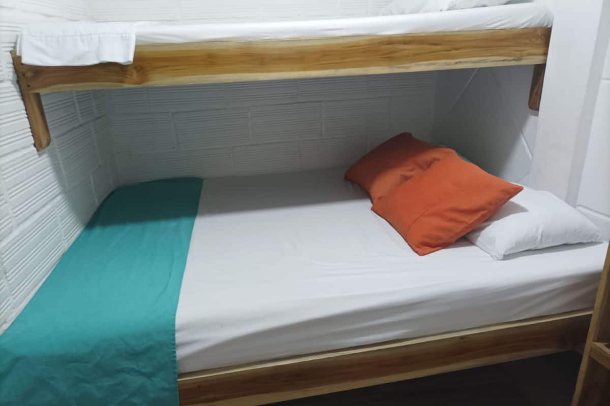 A bunk bed with a teal blanket and an orange pillow.