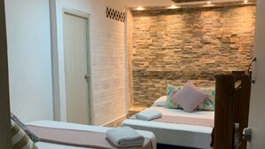 A bedroom with two beds, a stone wall, and a door. - Hostal Catalleya (Cartagena)
