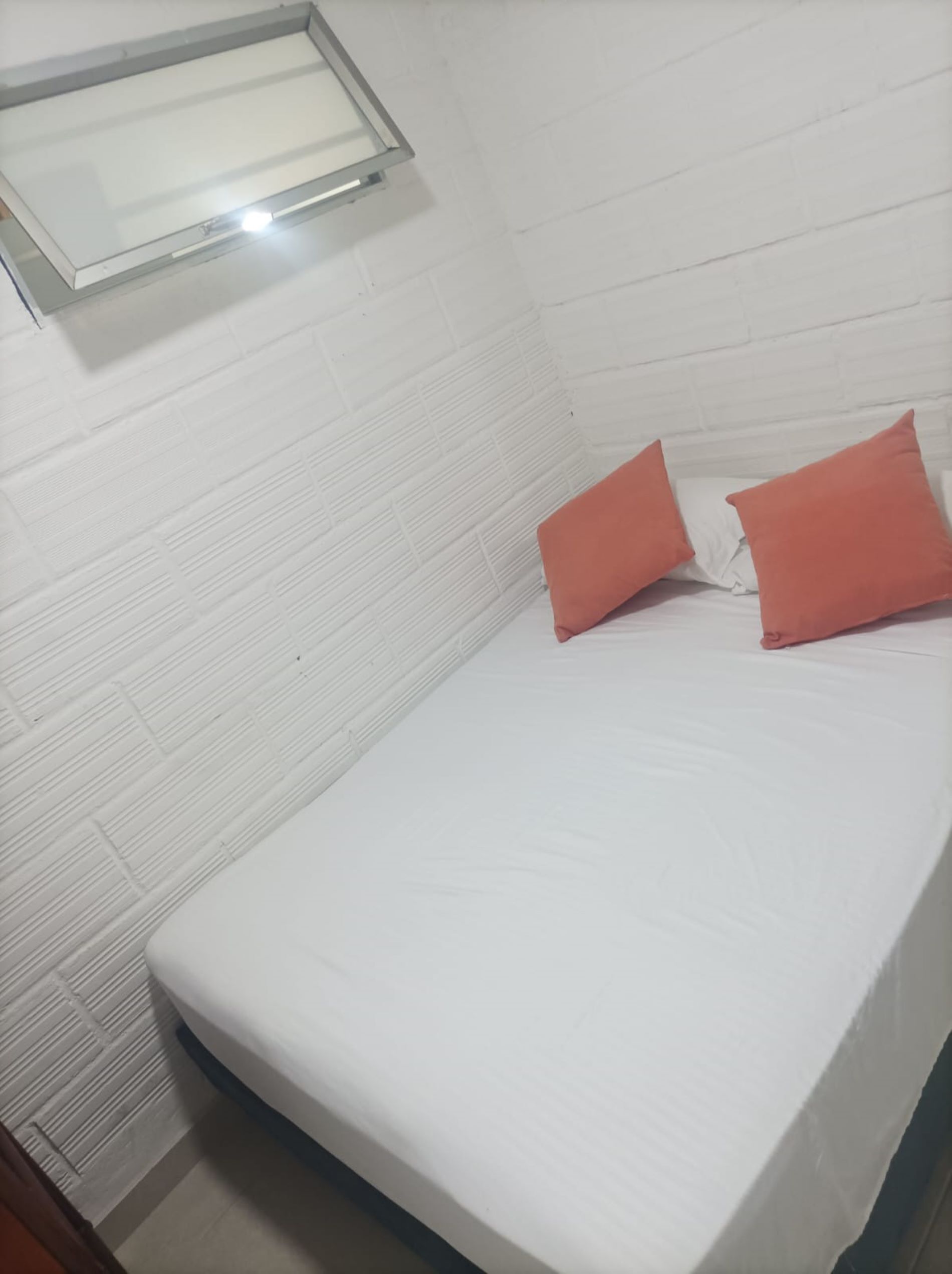 A small, single-bed room with white walls and a window.