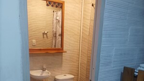 A bathroom with a toilet, sink, and mirror. - Hostal Catalleya (Cartagena)