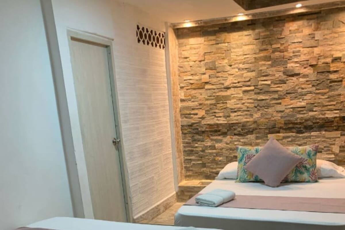 A hotel room with two beds, a stone wall, and a wooden floor.