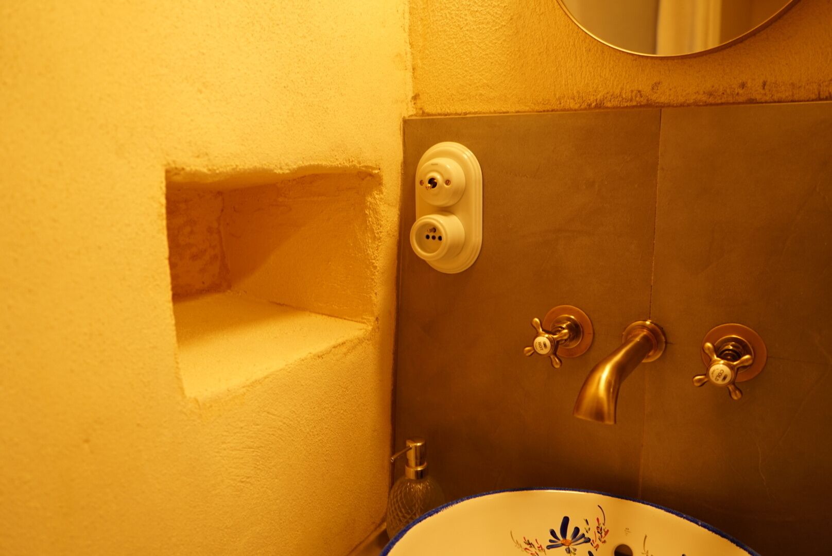 A bathroom with a sink, a mirror, and a shower with two faucets.