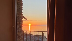 Une pièce offrant une vue sur le coucher de soleil, visible à travers une fenêtre ornée d’un cadre en pierre.