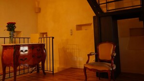 Une pièce avec une commode en bois, une chaise, un vase de fleurs et un escalier.