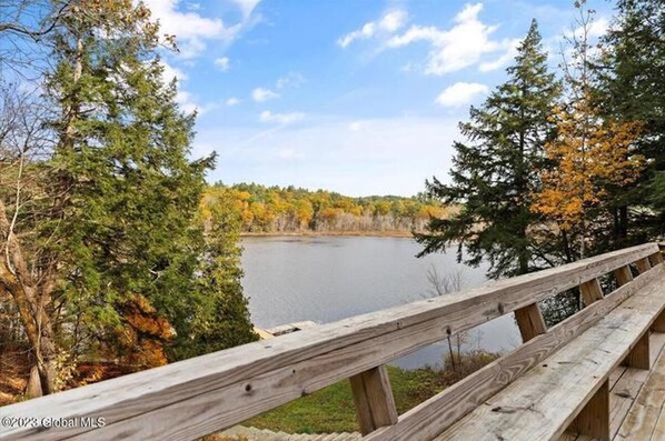 A wooden deck overlooking a lake with autumn-colored trees. - Beautiful lakefront house on Paradox lake with tremendous views and privacy. (Paradox)