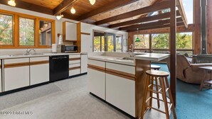 A spacious kitchen with white cabinetry, a central island, and a bar area. - Beautiful lakefront house on Paradox lake with tremendous views and privacy. (Paradox)