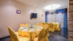 A conference room with round tables, yellow chairs, a chandelier, and a television on the wall. - Ying Rong Hotel (Chuxiong City)
