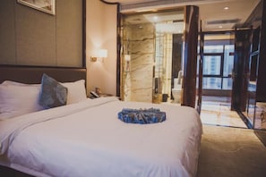 A hotel room with a large bed, a nightstand, a lamp, and a view through a glass door.