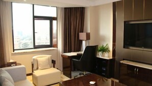 A modern hotel room with a large window, a sofa, a desk, a chair, a coffee table, and a TV. - Ying Rong Hotel (Chuxiong City)