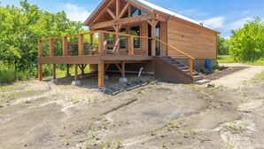 Une cabane en bois dotée d’une terrasse et d’un escalier menant à un porche abrité.