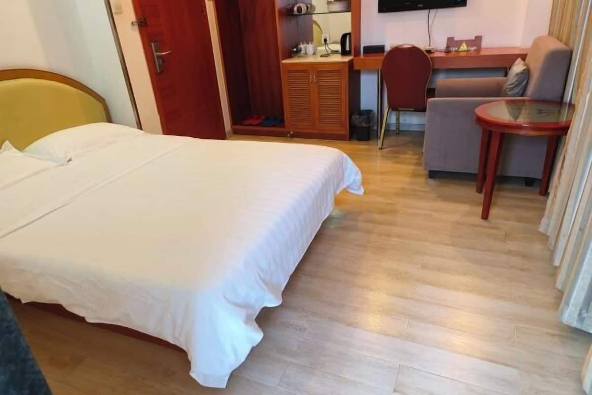 A hotel room with a bed, a desk, a chair, and a small table.
