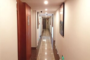 A hotel hallway with a polished floor, wooden doors, and framed pictures on the walls. - Xiamen Xiang An Boutique Hotel (Xiamen)