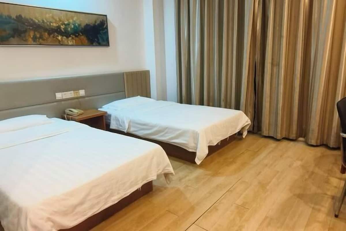 A hotel room with two beds, a painting on the wall, a telephone on the nightstand, and curtains.
