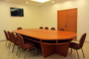 A conference room with a large oval table, eight chairs, a television on the wall, and a wooden door. - Xiamen Xiang An Boutique Hotel (Xiamen)